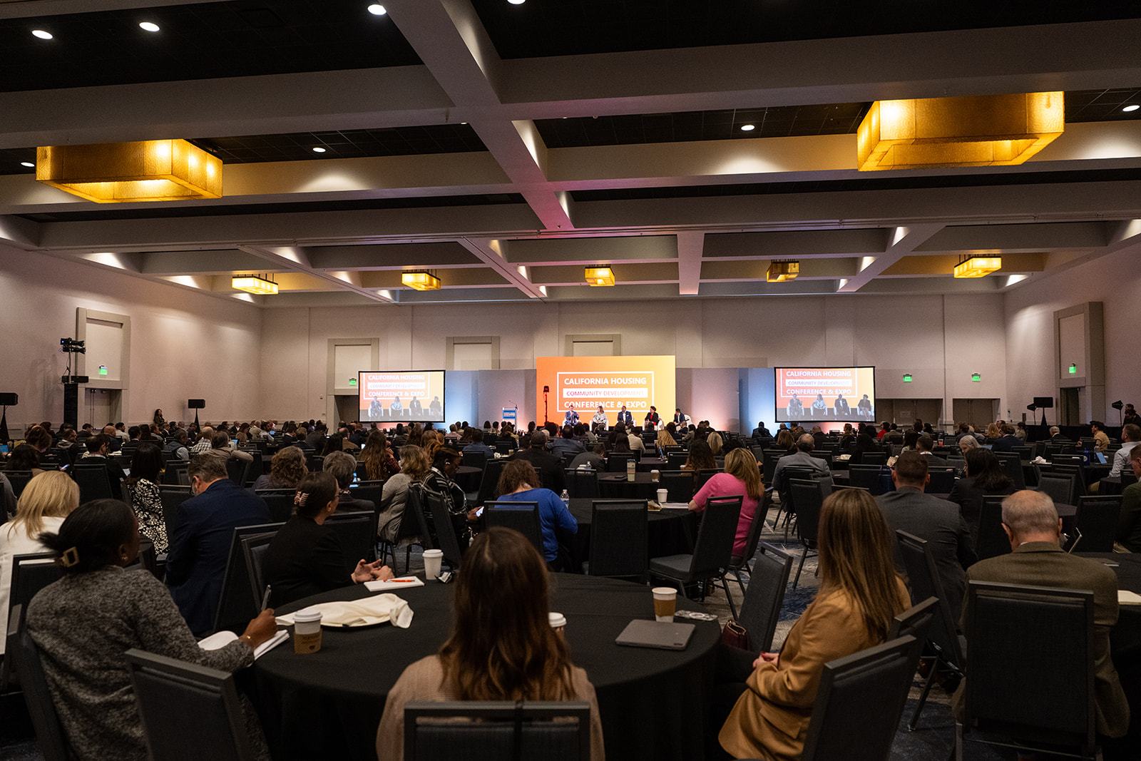 Attendees filling a large ballroom at round tables