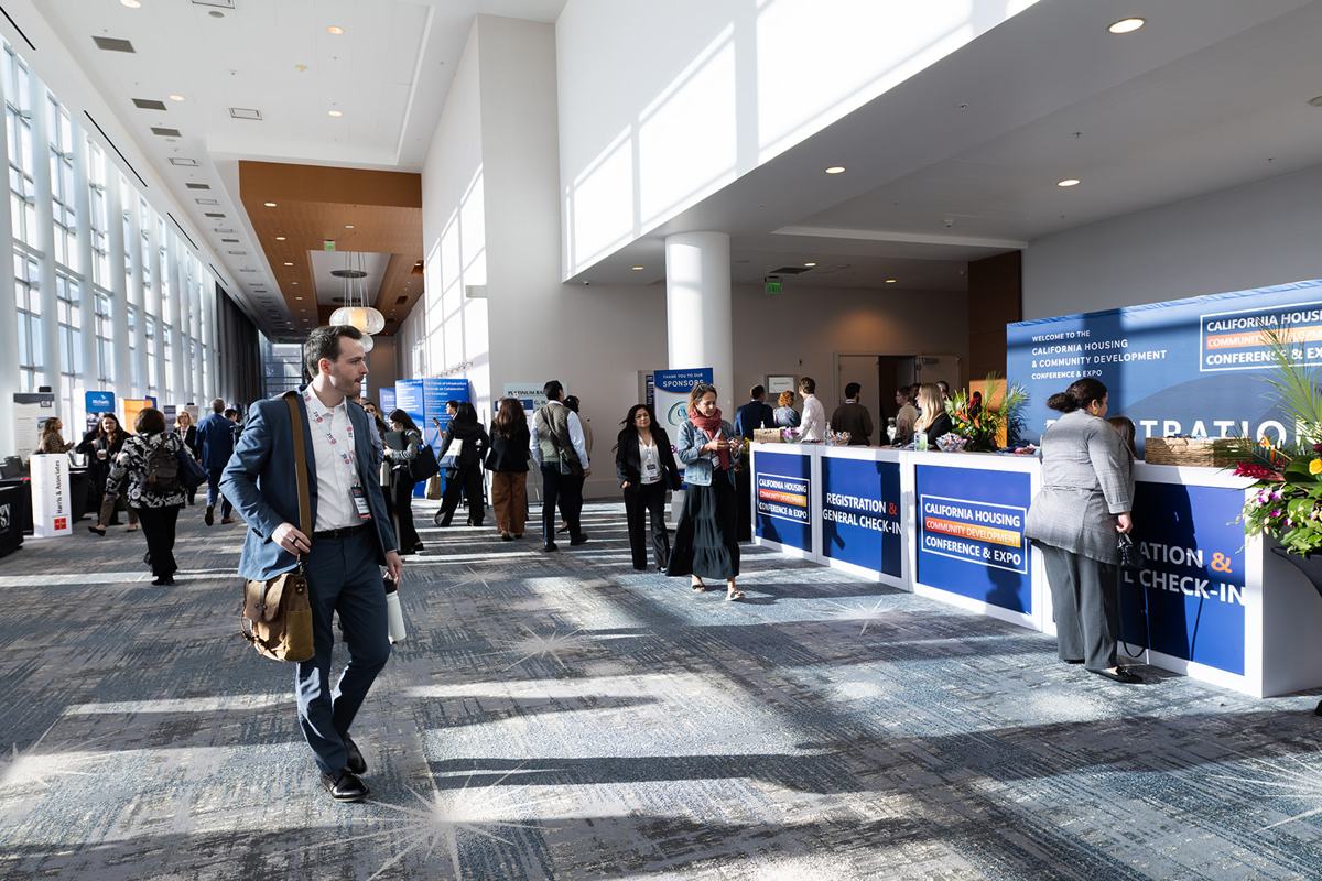 Attendees arriving at the registration area in a bright concourse