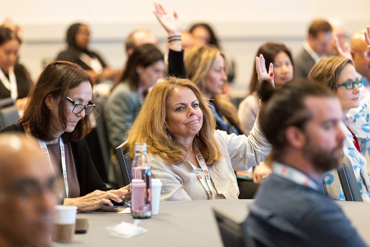 An engaged audience with a hand raised for a question